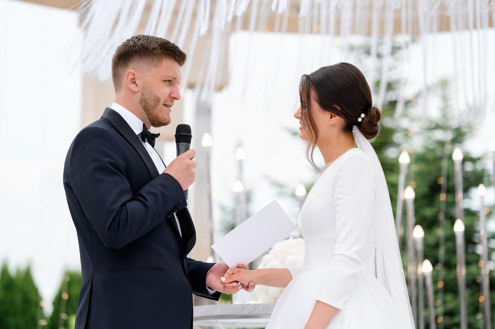 Bride and groom sharing vows at outdoor ceremony, perfect for wedding guest book and QR code to collect photos.